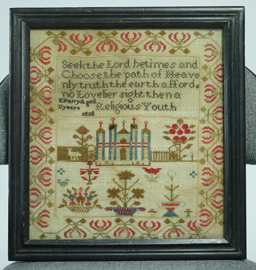 A framed 1828 cross stitch sampler dated 1828 by E Parry aged 11years. Embroidered in reds, greens and blues with religious verse and a central motif of a building, tree, flowers and sheep, above panel of spot motifs of